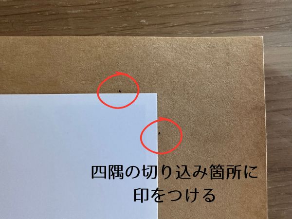 写真の四隅に切り込み用の印をつける様子